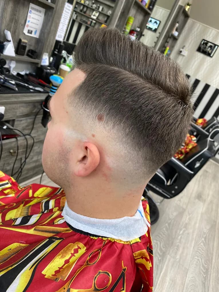 Mid-skin fade with a textured pompadour and a hard part