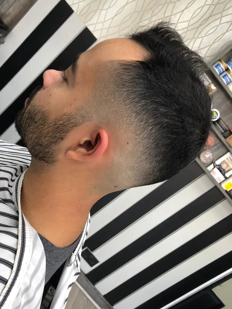 High drop fade with a short textured top and stubble beard