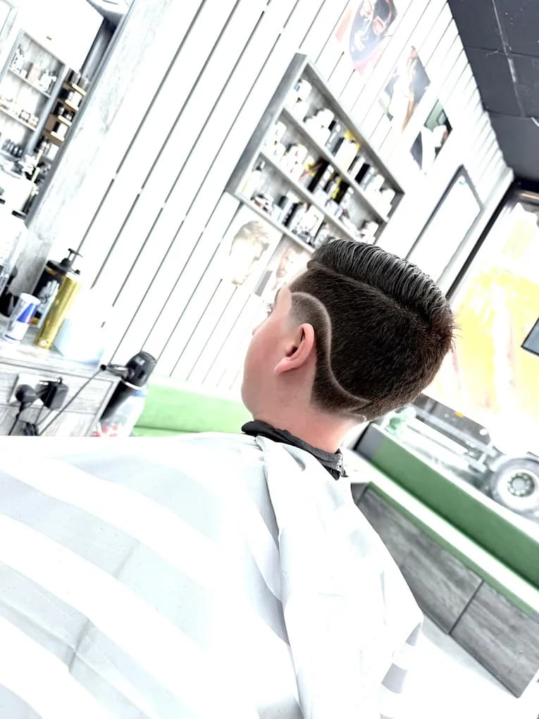 Slicked side-part with a curved surgical line design and drop fade